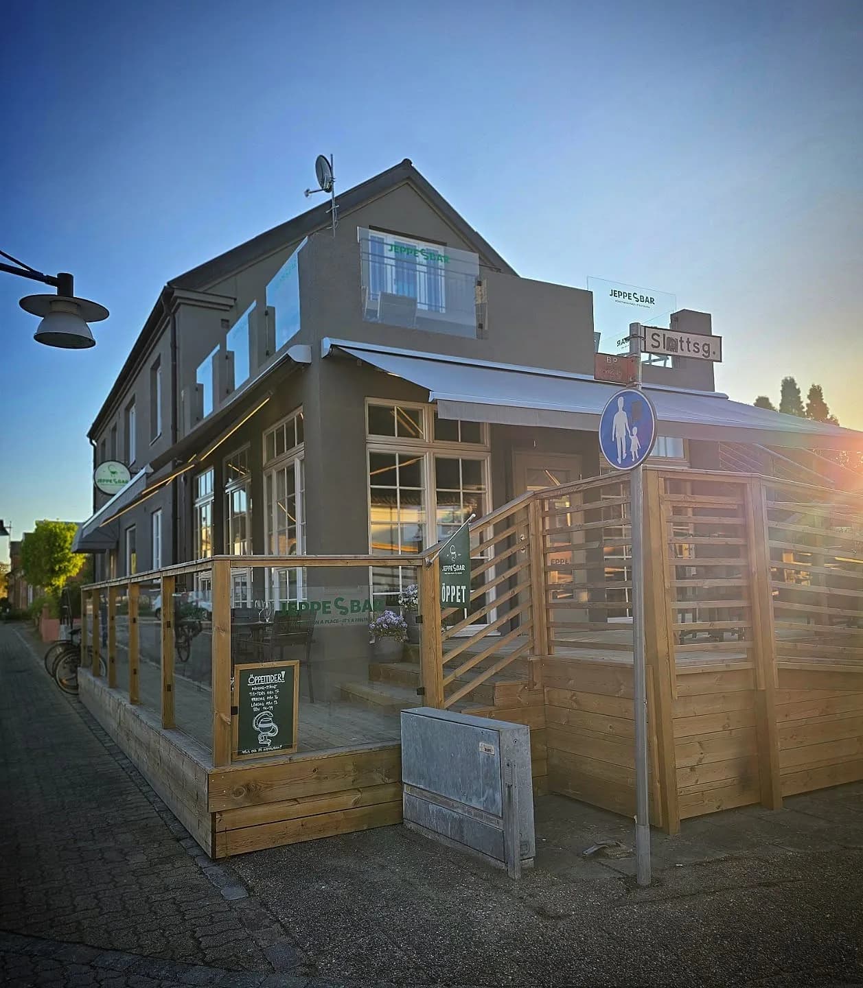 Huset på hörnet med uteserveringens trädäck och glasskivor mellan trästolpar