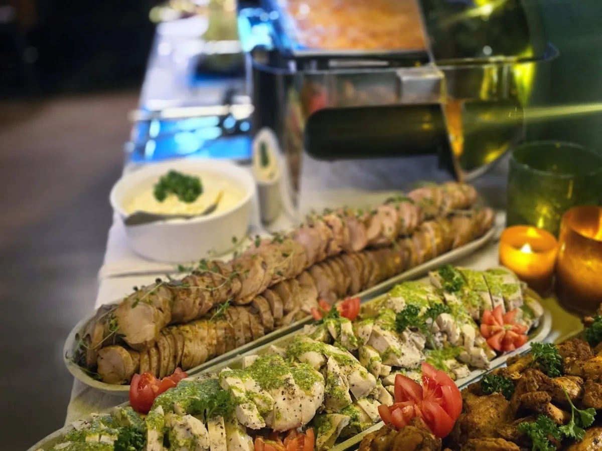 Lunchbuffén uppdukad i baren, med kött, kyckling och grönsaker på fat.